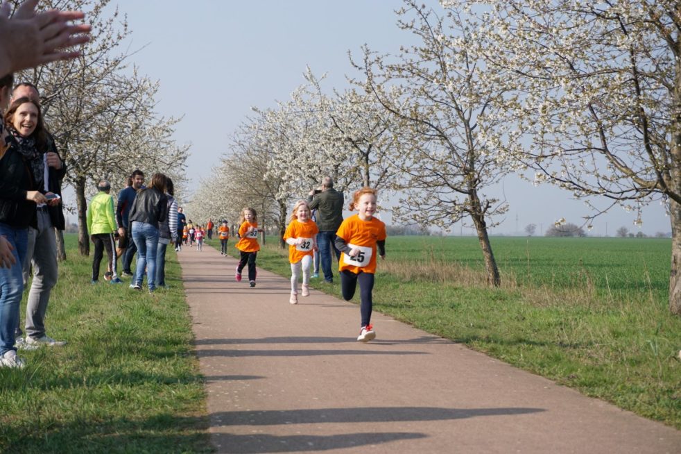 Kinder laufen an jubelnden Zuschauern vorbei